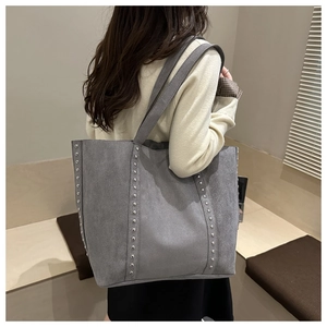Detail of gray suede tote bag with silver studs worn by a model from the back view