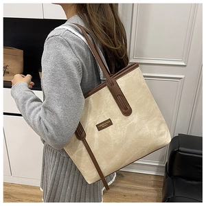 Side view of large cream canvas tote bag with brown leather straps on female model