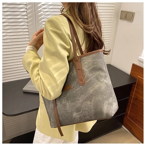 Detailed close-up of a large grey tote bag with premium brown leather handles and trim