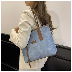 Model view of large denim tote bag with brown leather trim and shoulder straps