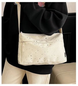 Détail du sac bandoulière en toile crème avec étoiles argentées et poches zippées