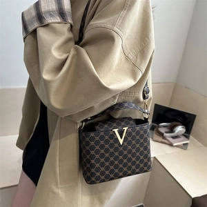 Brown vintage pattern shoulder bag with golden V clasp and detachable strap on model