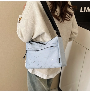 Détail d'un sac bandoulière en nylon bleu clair avec étoiles argentées et sangle noire