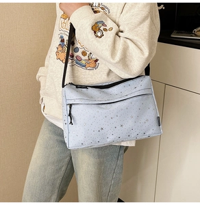 Détail du sac bandoulière en toile bleu clair avec motif d'étoiles et double fermeture