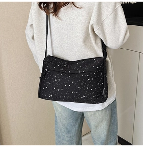 Gros plan sur un sac bandoulière en toile noire à motifs étoiles et bandoulière réglable