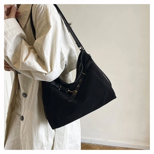 Détail d'un grand sac hobo noir en toile avec sangle en cuir et œillets métalliques