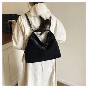 Vue détaillée d'un sac cabas en toile noire avec bandoulières en cuir et œillets métalliques
