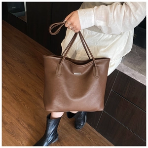Detailed texture of brown lychee grain leather tote bag with metallic logo plaque