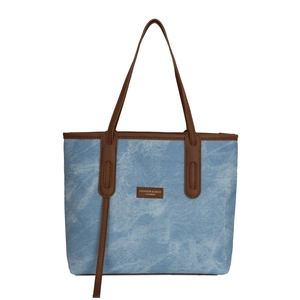 Blue denim tote bag with brown leather trim and handles in a minimalist casual design