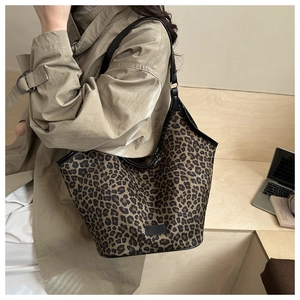 Gros plan d'un grand sac cabas en toile à imprimé léopard porté avec bandoulière noire