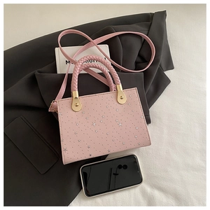 Pink pebbled leather bag with star studs and woven handle on a grey suit jacket