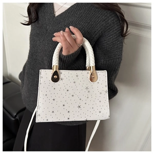 Detail of white star-textured handbag with woven handle and gold metal hardware link