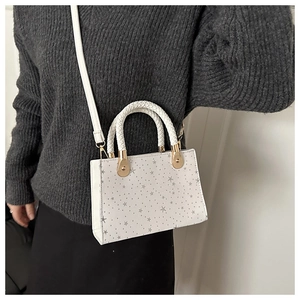 White rectangular crossbody bag with grey star pattern and woven double handles