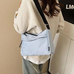 Sac bandoulière en toile bleu clair avec motif étoile argentée porté par un mannequin