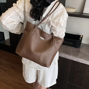 Brown lychee leather tote bag with silver plate shown in a natural indoor home setting