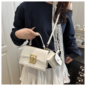 Close-up of a white patent leather handbag with gold buckle and a mini pouch charm