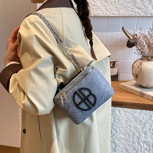 Mini sac caméra en feutre bleu avec chaîne dorée et logo BB porté par un mannequin