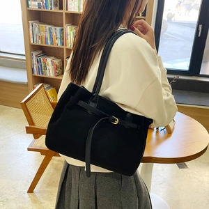 Minimalist black matte tote bag with thin leather straps shown on a model's shoulder