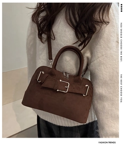 Detail of a brown suede handbag with silver buckle decoration and double zipper closure