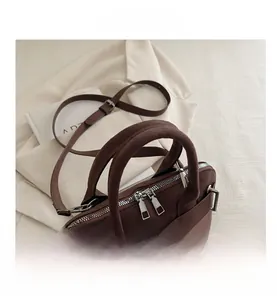 Detail view of dark brown suede handbag with silver zippers and textured leather stitching