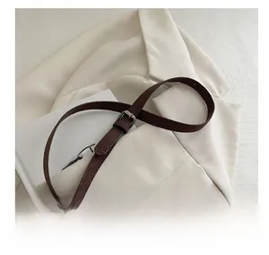 Adjustable brown suede shoulder strap with silver buckle on elegant white blazer