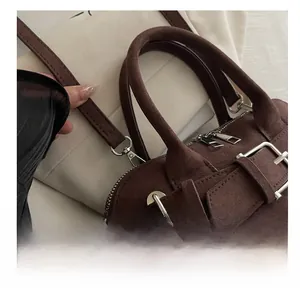 Detail view of silver metal hooks and handles on a textured dark brown suede handbag