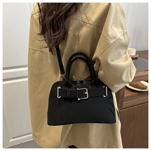 Fashionable black suede handbag with silver buckle worn in a cozy cafe setting