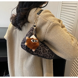 Detail of leopard print shoulder bag with chain strap and cute plush toy charm accessory
