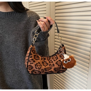 Macro shot of leopard print handbag with plush charm and metal chain strap detail