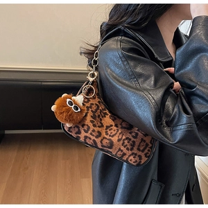 Close-up of leopard print suede shoulder bag with brown plush charm and gold chain