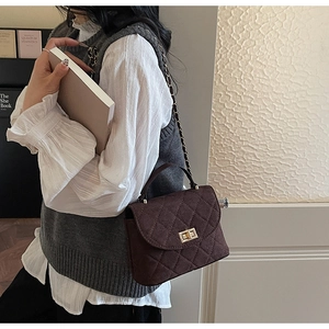Detailed close-up of dark brown quilted suede handbag with gold twist lock and chain strap
