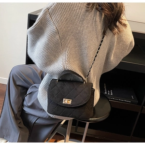 Detail of black quilted chain bag featuring gold hardware and elegant crossbody styling