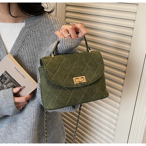 Close-up of dark green quilted handbag with gold clasp and textured wool material