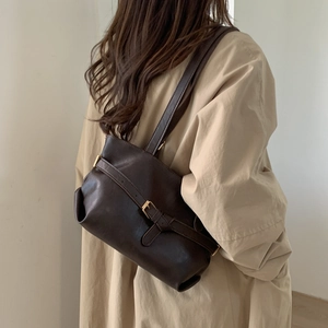 Retro brown leather tote bag with metallic buckle shown in a stylish over-the-shoulder pose
