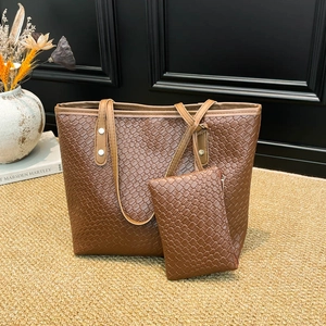 Ensemble sac cabas et pochette tressés marron avec rivets argentés sur tapis