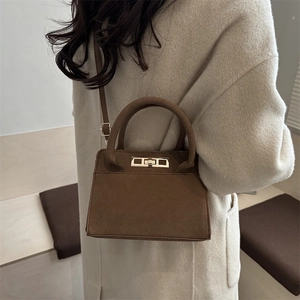 Classic dark brown suede crossbody bag with elegant gold clasp shown on a model