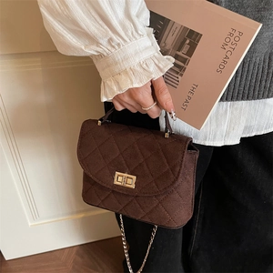Quilted dark brown crossbody bag with gold hardware and chain strap shown by a model
