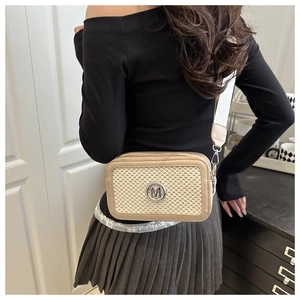 Détails du sac caméra avec logo M, texture tissée et bandoulière géométrique
