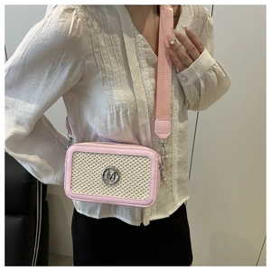 Detail of pink woven crossbody bag with silver M logo and wide fabric shoulder strap