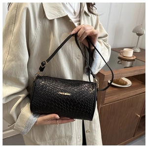 Détail du sac cylindre noir avec texture tressée et logo métallique doré élégant