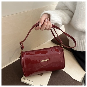 Détail du sac cylindrique en cuir verni bordeaux avec logo doré fashion