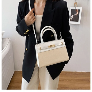 White leather and woven straw crossbody bag with golden hardware shown in home setting