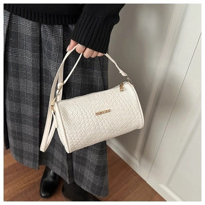 Détail du sac cylindrique tressé blanc montrant la plaque dorée Fashion et la texture