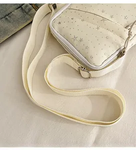 Detail of adjustable woven nylon strap and silver star studs on creamy white PU leather bag