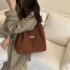Brown pleated large capacity tote bag with fashion label shown in a lifestyle setting