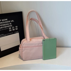 Pink nylon handbag size comparison with a tablet, featuring front zipper pocket