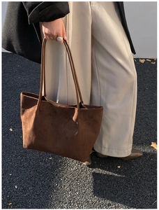 Close-up of brown matte tote bag with long straps worn by a model in a winter coat