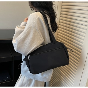 Detail view of black canvas shoulder bag with side drawstring and functional zipper pocket