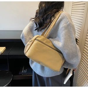 Detail of trendy creamy yellow rectangular shoulder bag with dual handles and zipper closure
