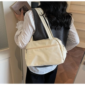 Rear view of a minimalist cream nylon tote bag featuring a practical front zipper pocket